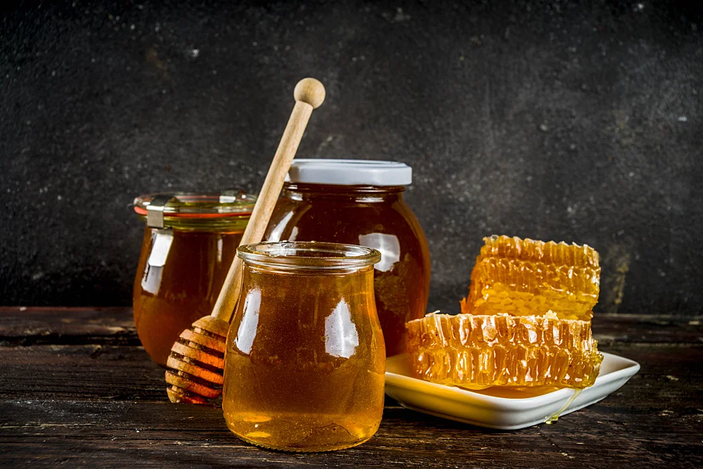 Organic farm honey in jars with honeycombs
